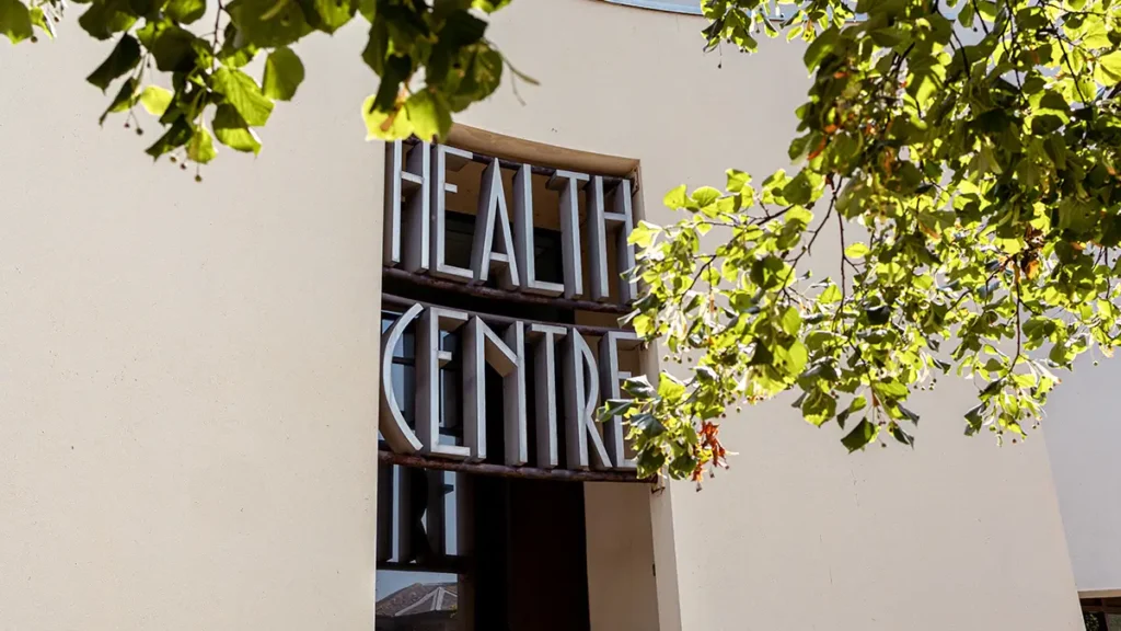 Atrium Health Centre signage at Brewery Square Dorchester, partially framed by tree leaves